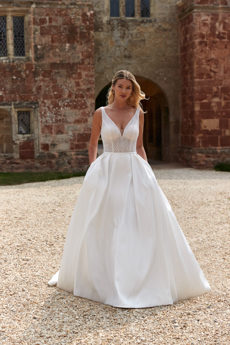 Bride wearing the Bronte ivory A-line gown with pearl-embellished sheer bodice in front of a stone building