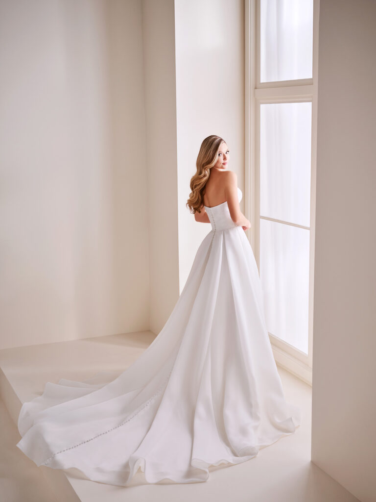 Rear view of the E408 bridal gown showing the strapless back and flowing satin train