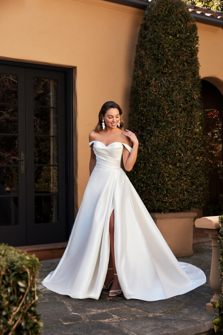 Full-length front view of the Ansel Y3108LB ivory ball gown with off-the-shoulder neckline and split satin skirt