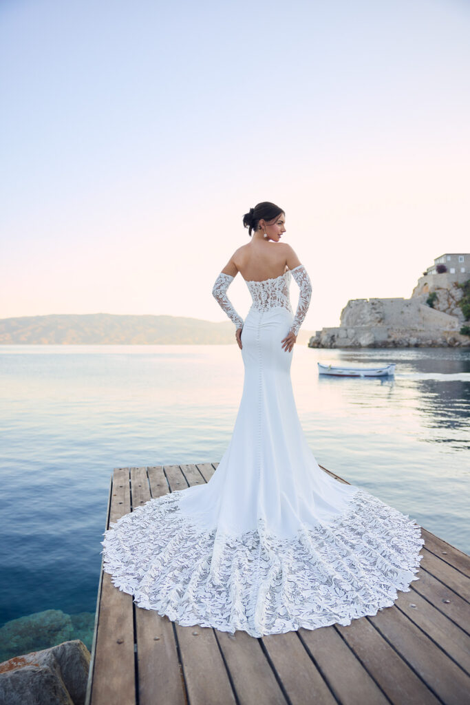 Full-length rear view of the Lucie bridal gown showing the lace sleeves and scalloped train