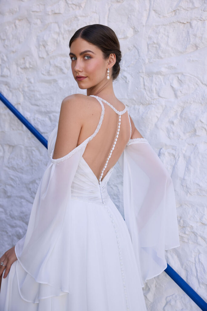Rear view of the Abby bridal gown with beaded back straps and flowing fabric held outward
