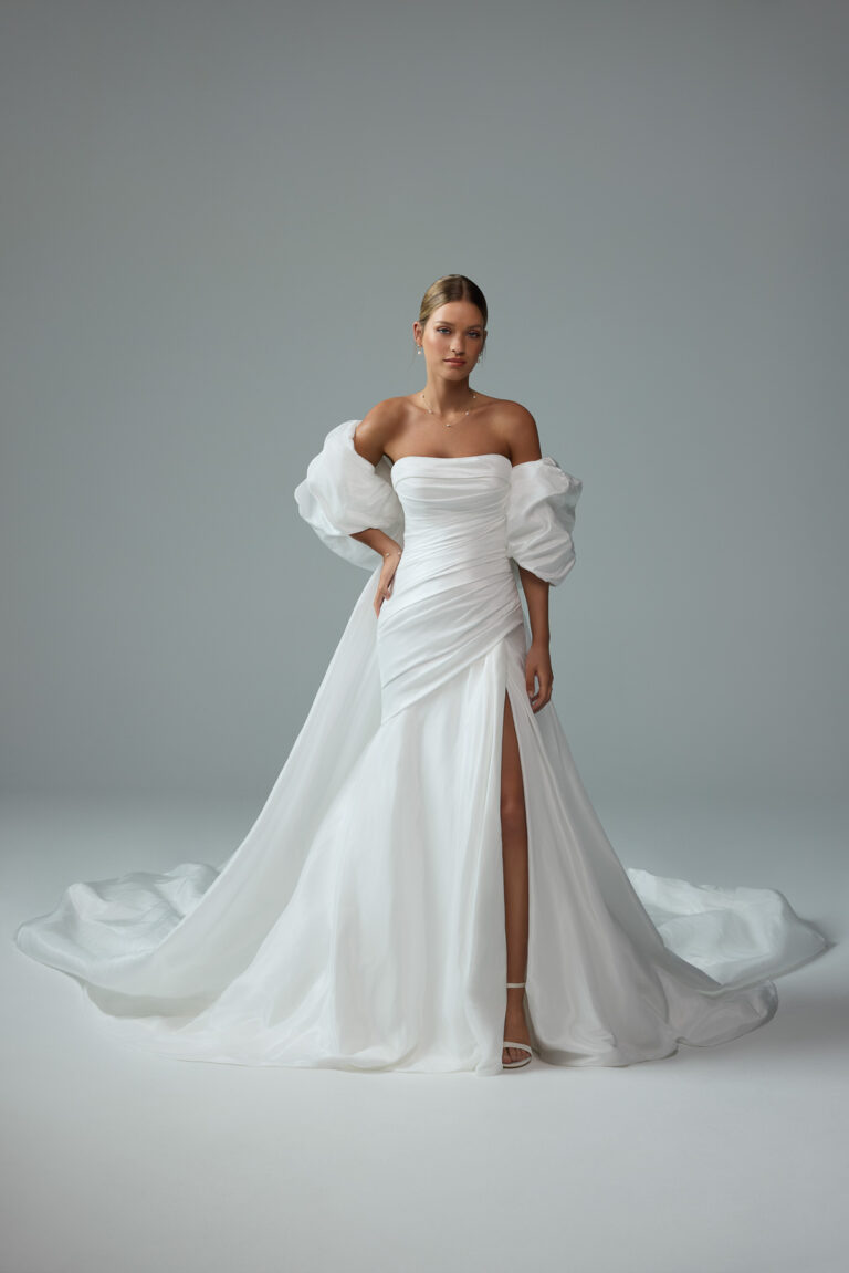 Full-length front view of the Cody Y3214FILB ivory fit-and-flare gown with straight neckline, side slit and draped sleeves