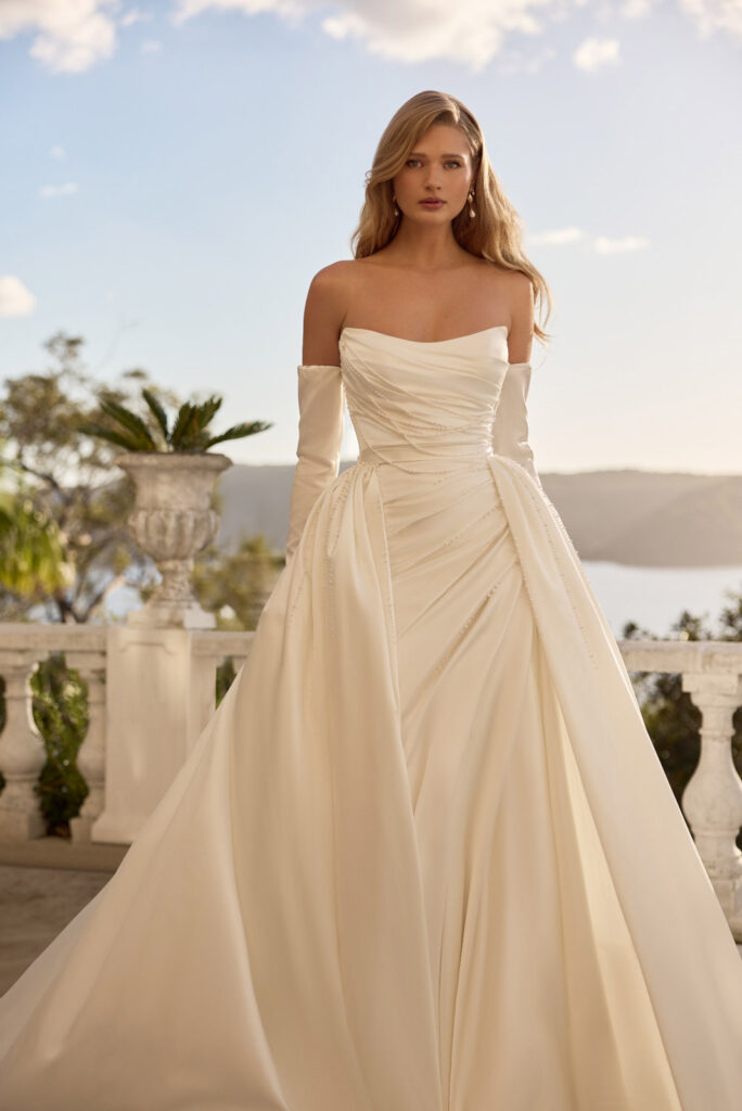 Bride in a flowing ivory gown with long draped sleeves